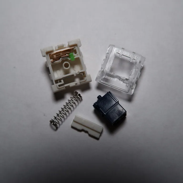 A Kailh BOX Navy taken apart: clear top housing, navy stem, spring and the click bar