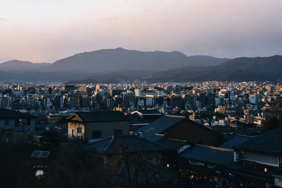 Cityscape at dusk, with mountains in background.