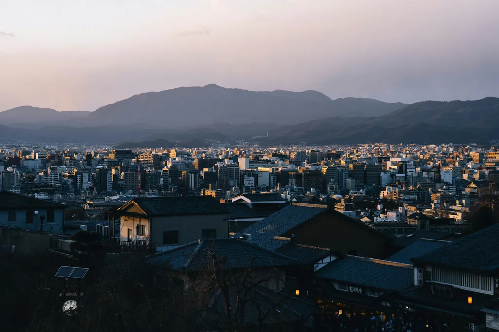 Cityscape at dusk, with mountains in background.